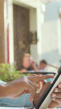 Güzel görünümlü, 30 yaşında, sakallı, Afro-amerikalı, rahat bir açık hava kafesinde oturan ve gündüzleri tablet bilgisayarında ihtiyaç duyulan programları gözden geçiren.