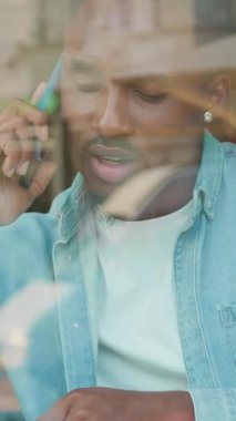 Çekici, 30 yaşında, modern, sakallı, siyah derili bir adam rahat bir cadde kafenin penceresinin yanındaki masada otururken iş konuşması yapıyor.