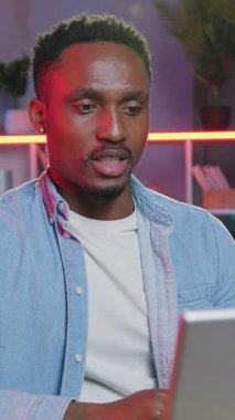 İş arkadaşlarıyla video konferansı sırasında bilgisayar başında oturan ve akşamları merkez ofisten ortak iş stratejisinde onlara danışan 30 yaşında başarılı, siyah tenli bir adamın uzaktan çalışma konsepti.