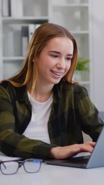 Ofiste çalışırken dizüstü bilgisayar kullanan gülümseyen bir kadın. İş kadını evde bilgisayar ekranına bakarak serbest çalışmanın tadını çıkarıyor. Yavaş çekim.