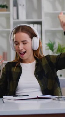 Müzik dinleyen, kulaklıkla şarkı söyleyen, dans eden, dizüstü bilgisayarla iletişim kuran genç bir kadın. Duygusal kadın portresi. Modern kulaklıkla müzik dinleyen kaygısız bir kadın. Yavaş çekim.