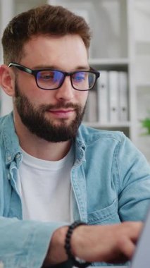 Oturma odasında masa başında otururken laptopta çalışan yakışıklı beyaz adam. Serbest çalışan profesyonel bir erkek, evden önemli bir e-posta yazıyor. Yavaş çekim.