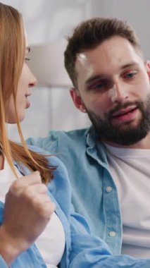 Mobil ekran seyreden mutlu bin yıllık erkek ve kadın evdeki rahat oturma odasında kanepede oturuyor. Kadın ve erkek akıllı telefon kullanarak gülümsüyor. Yavaş çekim.