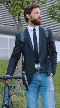 Şehir modern binasının yakınlarındaki yaya yolunda bisikletle yürüyen, iş kıyafetleriyle bakımlı, şık, genç ve şık bir ofis çalışanına yakın durun.