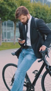 Çekici bir stil. İyi modda. 30 yaşında, sakallı, siyah ceketli, kot pantolonlu, bisiklete yaslanmış ve akıllı telefonuyla şehir otobüsü, tren istasyonu ya da havaalanı yakınlarındaki akıllı telefonuna mesaj yazıyor.