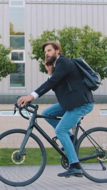 İşe bisikletle giderken akıllı telefondan konuşan 30 yaşında, kasıtlı, kendine güvenen bir ofis çalışanının portresi.