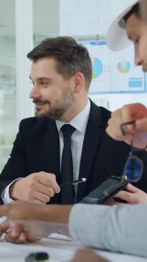 Görüşme odasındaki planlar üzerine yoğunlaşmış sakallı patron ve kadın ortakla görüşen oldukça yetenekli ve çok ırklı müteahhitler.