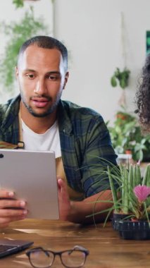 Mutlu Afro-Amerikan erkek ve kadın çiçekçilerin portresi çiçekçide dijital tablet kullanarak çalışan ve konuşan çiçekçiler. İnsanlar ve iş kavramı. Yavaş çekim.