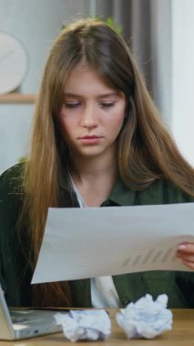 İyi görünümlü, kafası karışmış 25 yaşında bir kız programcının iş yerinde oturup bilgisayardaki belge ve verilerle çalışması ve sonra da buruşmuş kağıtları kızgın bir şekilde başka bir kağıda atması.