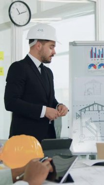 Yakışıklı, ciddi, ciddi, maksatlı, sakallı patronun portresi. Tecrübeli yönetici yarış uzmanları, inşaat firması uzmanları, yönetim kurulundaki yeni bina inşaatının ayrıntılarını konuşuyor ve tartışıyorlar.