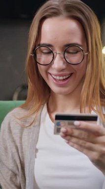 İnternetten akıllı telefon alışverişi yapan gözlüklü güzel bir kadının portresi kredi kartını giriyor. Para transfer ederken kredi kartı kullanan, online alışveriş yapan, modern mutfaktan yemek sipariş eden bir kız. Yavaş çekim.