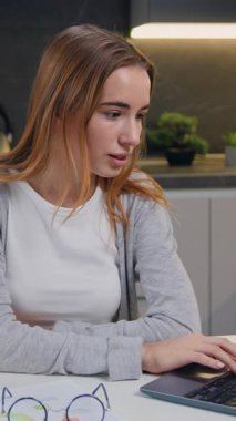 İş kadını, dairesindeki kameraya bakarak yaşam tarzını beğeniyor. Kameraya bakıp beyaz mutfak arka planında poz veren neşeli beyaz bir kızın portresi. Yavaş çekim.