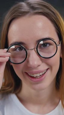 Kameraya bakıp gülümseyen ve evdeki modern mutfakta gözlüğünü çıkaran güzel kız. Yavaş çekim.