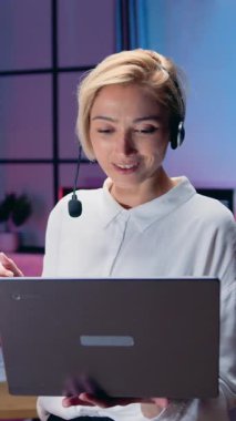 Kablosuz kulaklıkla konuşma sırasında dizüstü bilgisayarı tutan ve şeffaf tahtaya önemli notlar yazan oldukça başarılı akıllı, yüksek yetenekli 40 yaşında kadın ofis yöneticisi.