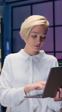 Şeffaf panonun yanında çalışan ve kameraya samimi bir gülümsemeyle bakan 40 yaşında, kendine güvenen, çekici, kendine güvenen bir kadın ofis müdürünün portresi.