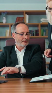 Good-looking experienced professional bearded businessman signating business documents brought by his pretty hardworking light haired woman-helper,workflow in office,accelerated motion