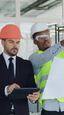 Çekici, zeki, sakallı inşaat şirketinin CEO 'su. Yeni inşa edilmiş ofis binasını teftiş ediyor. Siyah şapkalı ana mühendisi ile birlikte.