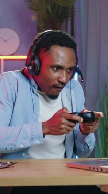 Çekici duygusal mutsuz, 30 yaşında, siyah derili, kablosuz kulaklık takan oyun konsolu kullanarak bilgisayar oyunu oynayan ve oyunu kaybettiğinde hayal kırıklığına uğrayan,