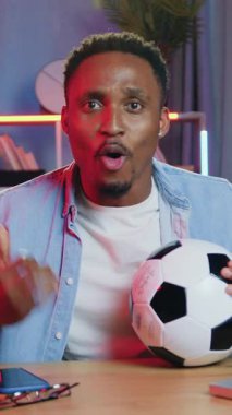 Çekici, mutlu, mutlu, 30 yaşında Afro-Amerikalı 'nın elinde futbol topuyla akşamları evde spor maçı seyrettiği ve en sevdiği takımı komik tepkilerle yenmenin keyfini çıkardığı bir konsept.