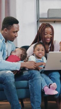 Sevimli gülümseyen genç Afro-Amerikan çifti ve üç çocuğu yeni edinilmiş evlerinde kanepede oturuyor karton paketlerin arasında taşınma günü, ön manzara