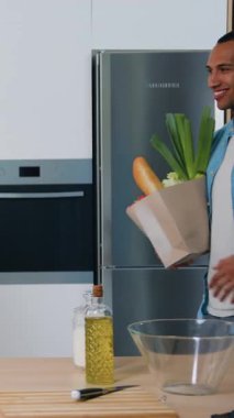 Çok kültürlü çiftler marketten aldıkları kese kağıdından taze sebzeleri alıyorlar. Afro-Amerikalı erkek ve beyaz kadın süpermarketten alışveriş yaptıktan sonra kese kağıdı tutuyorlar. Yavaş çekim.