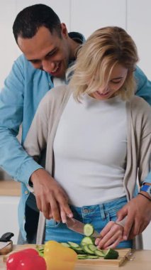 Mutlu erkek ve kadın, ev mutfağında sebzelerle sağlıklı salata hazırlıyor ve pişiriyor. Birlikte gülerek yemek pişiren çift sağlıklı yemek hazırlıyor. Afiyet olsun. Yavaş çekim.