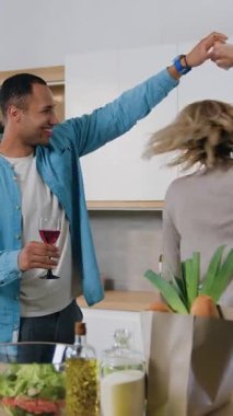 Kadın ve erkek sıcak mutfakta kadeh tokuşturup içiyorlar. Aşık mutlu çift mutfakta romantik bir akşam dansı yapar. Yavaş çekim.