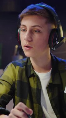 Genç erkek blogcu evde, mutfakta akıllı telefonuyla blog yazıyor. Grafik ve çizelge gösteren çocuk çevrimiçi yayın yapıyor, video eğitimi alıyor. Yavaş çekim.