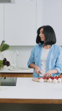 Çekici, mutlu, gülümseyen bir çift aile yemeği pişirmek için modern mutfaklarda bir araya geliyor.