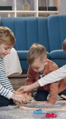 Çekici sükuneti yakın çekim iyi ruh hali içinde iki büyük oğlan ve en küçük kardeşi araba pisti inşa ederken yumuşak halıda birlikte oynuyorlar.