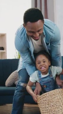 Yakışıklı, neşeli, koyu tenli bir baba elinde sepetle annesinin yanında oturan küçük kızı ve diğer kızı sırasının gelmesini bekliyor.