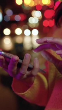 Şehir sokaklarının renkli ışıklarının arka planında el ele tutuşan iyi korunan kadın elleri, yavaş çekim, kapatın.