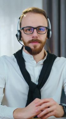 Çekici, başarılı, yetenekli, 30 yaşında, kulaklık takmış, kameraya bakan, güzel tasarlanmış bir odanın arka planında samimi bir şekilde gülümseyen modern bir adam.