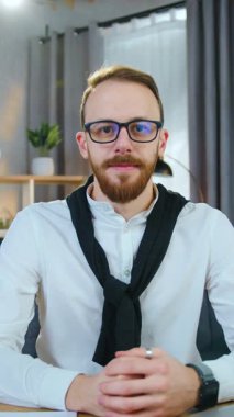 Yakışıklı, yetenekli, evli, beyaz tişörtlü, sakallı genç adam kameraya doğru gülümsüyor. Çağdaş odada, masada otururken, yavaşça, yavaşça.