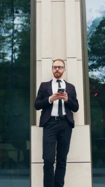 Şehirdeki iş yerlerinde e-posta yazan şık, yakışıklı bir işadamı. Sosyal ağ dalavereci adam akıllı telefondaki mobil uygulamayı kullanarak online mağazada ürünlere göz atıyor. Yavaş çekim.