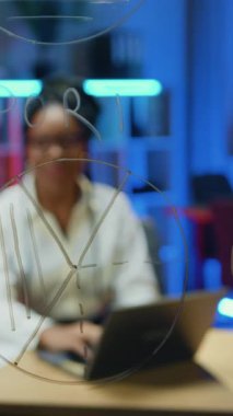 İnternet iş kanalı için video kamera kullanarak yeni blog içeriğini çeken beyaz bluz giyen başarılı Afrikalı iş kadınlarının cam panosu aracılığıyla belirsiz bir görüş.