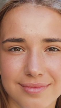 Cazibeli, kaygısız genç sarışın modern şehir binasının yanında kameranın önünde duruyor ve rüzgar saçlarını ön tarafa savuruyor.