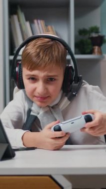 Boy in headphone playing video game with wireless controller with joy of victory. Emotionally winning yes hand gesture victory having fun with controller addiction to videogaming. Slow motion.