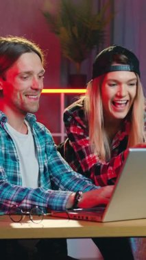 Çekici, olumlu, modern 25 'li yaşlarda bir adam ve kız arkadaşı dizüstü bilgisayar ekranında izliyor ve haber okuyor ya da gece aydınlatmalı, rahat bir odada ilginç bir film arıyor.