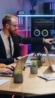 İyi görünümlü, kararlı, profesyonel erkek ve kadın ofis çalışanları modern çalışma odasında gece ışıklarıyla masaya oturur ve interaktif ekranda dünya istatistikleri verileriyle tanışırlar.