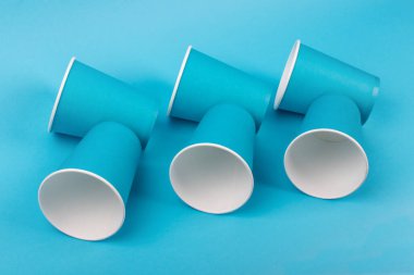 Mavi arka planda izole edilmiş kağıt bardaklar. Çevre dostu, gübrelenebilir sofra takımı, tek kullanımlık, geri dönüşümlü beyaz arka plan. Sıfır plastik, gezegen koruma, plastiği durdur. Geri dönüşüm kavramı