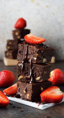 Kahverengi arka planda çilekli çikolatalı brownie parçaları.