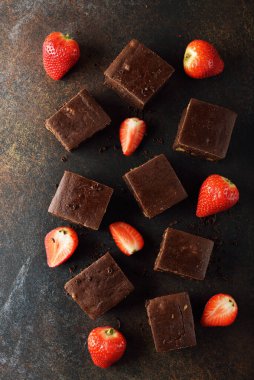 Kahverengi arka planda çilekli çikolatalı brownie parçaları.