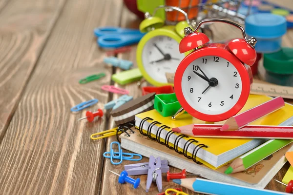 Red alarm clock and colorful school supplies — Stock fotografie