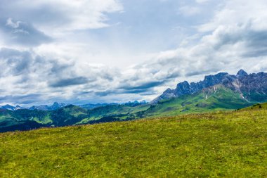 İtalya, Alpe di Siusi, Seiser Alm Sassolungo Langkofel Dolomite ile birlikte, arkasında dağ olan büyük yeşil bir tarla.