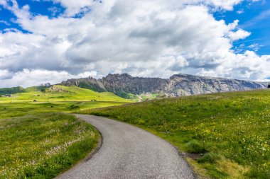 Alpe di Siusi, Seiser Alm Sassolungo Langkofel Dolomite ile birlikte, yemyeşil bir arazi panoramasında yayan bir yürüyüş yolu.