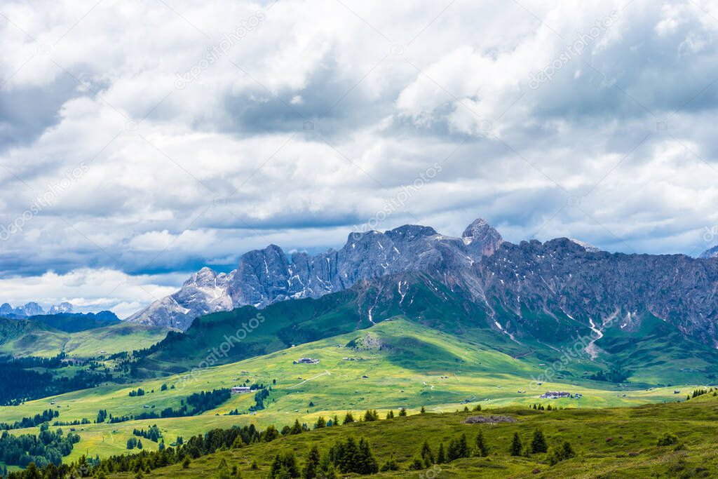 Italy, Alpe di Siusi, Seiser Alm with Sassolungo Langkofel Dolomite, a large green field with a mountain in the background