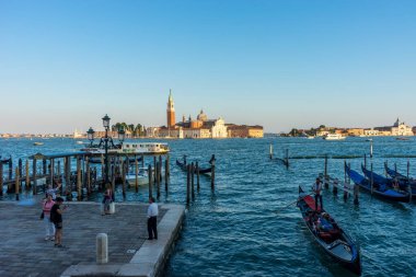 Venedik, İtalya - 30 Haziran 2018: Venedik, İtalya 'da arka planda Saint Mark Meydanı ve San Giorgio di Maggiore Kilisesi' nin demirlediği Gondolas