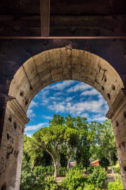 Roma, İtalya - 23 Haziran 2018: Roma forumunun kalıntıları, Flavian Amfitiyatrosu olarak da bilinen Roma Kolezyumu 'nun (Kolezyum, Kolezyum) girişindeki geçitin kapısından görülüyor. Ünlü dünya simgesi. Manzaralı şehir manzarası.