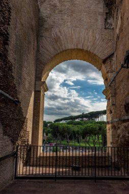 Roma, İtalya - 23 Haziran 2018: Roma forumunun kalıntıları, Flavian Amfitiyatrosu olarak da bilinen Roma Kolezyumu 'nun (Kolezyum, Kolezyum) girişindeki geçitin kapısından görülüyor. Ünlü dünya simgesi. Manzaralı şehir manzarası.